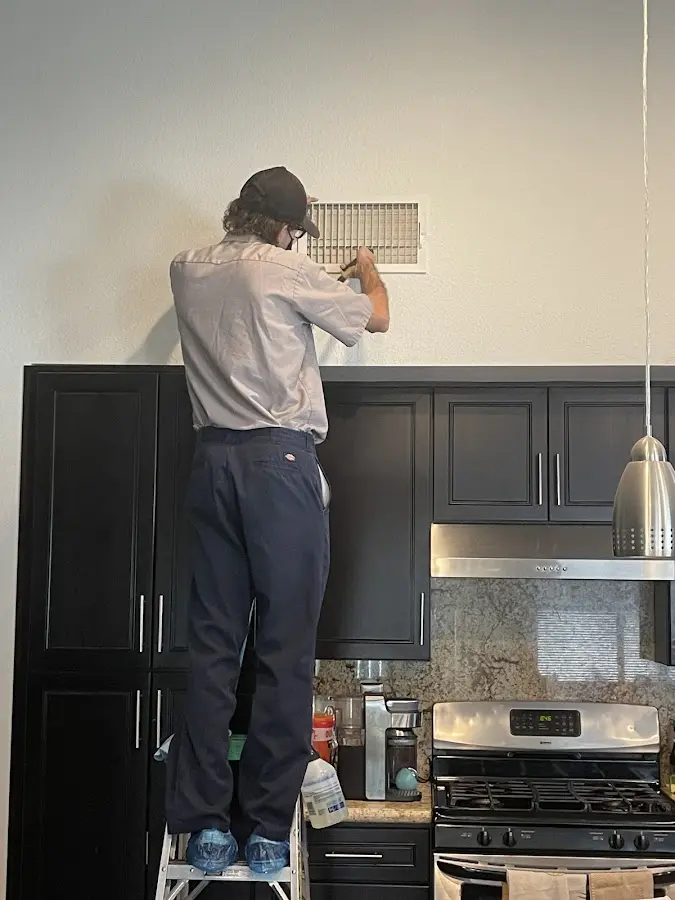 Technician inspecting an air vent during HVAC service in Dayton
